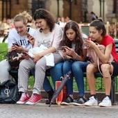 dzieci siedza na lawce z telefonami